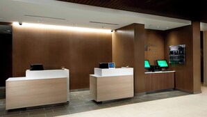 A reception area with two reception desks, a wall-mounted digital display, and a poster. - Courtyard by Marriott Charlotte Fort Mill, SC (Fort Mill)
