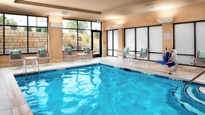 An indoor swimming pool with clear blue water, surrounded by lounge chairs and a stone wall. - Courtyard by Marriott Charlotte Fort Mill, SC (Fort Mill)