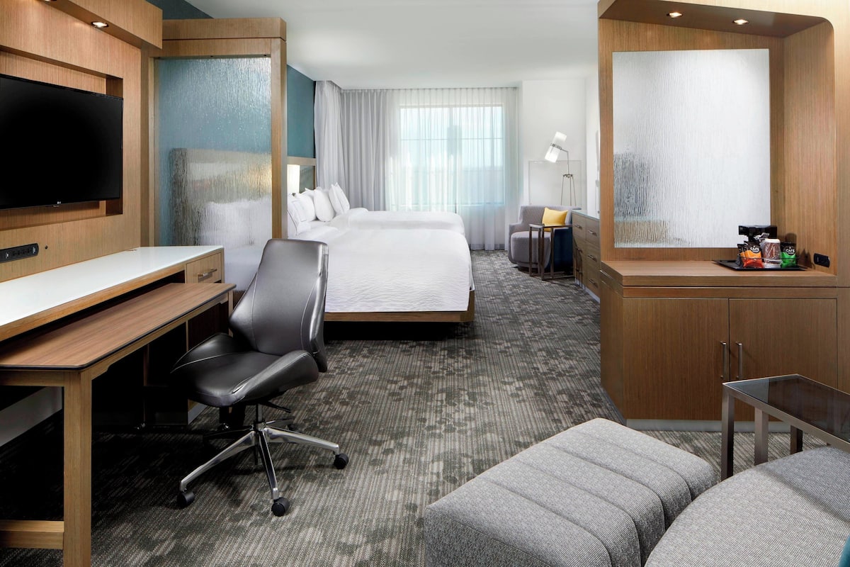 Een hotelkamer met een bed, bureau, stoel en een televisie.