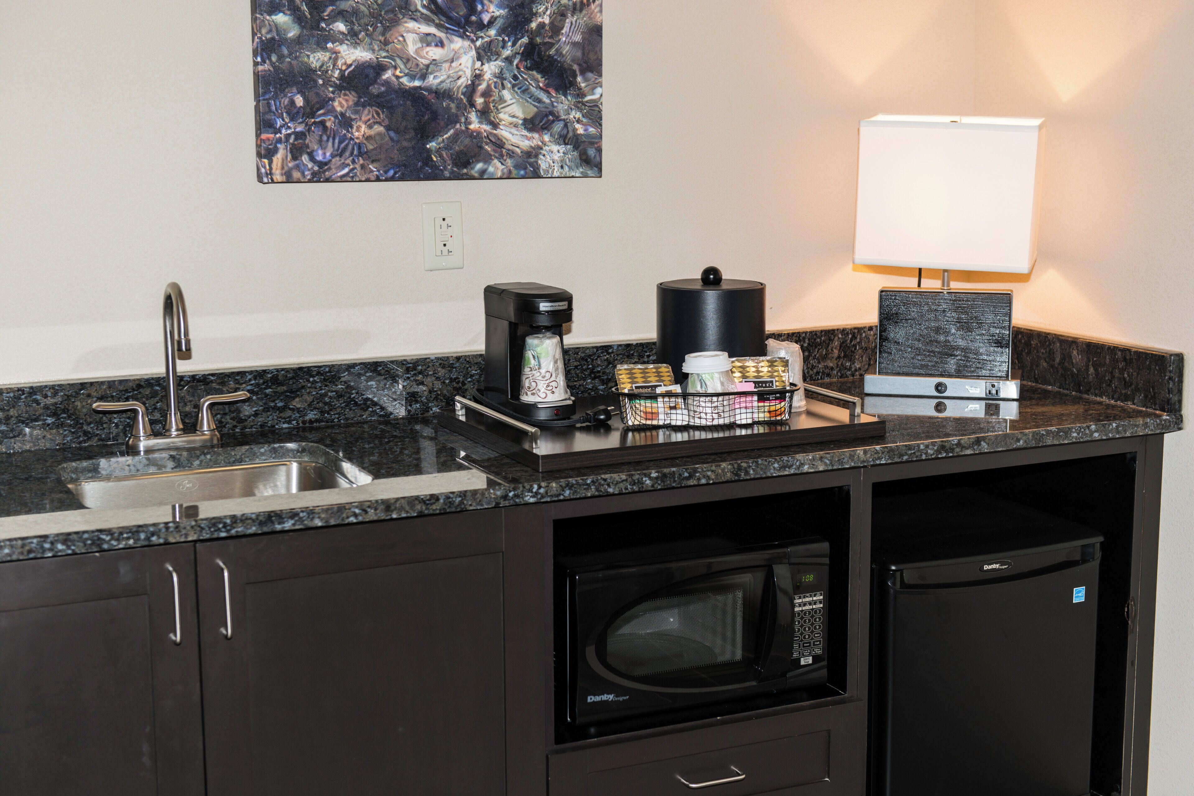 Una kitchenette equipada con cafetera, microondas y un refrigerador pequeño.