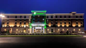 Un hotel Holiday Inn con fachada moderna, entrada iluminada y aparcamiento.
