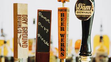 Un grifo con etiquetas para diferentes cervezas, incluyendo 'The Dam Brewhaus' y 'Paduca Beerworks'.