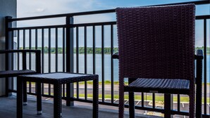Un balcon avec des fauteuils en osier et une vue sur une étendue d’eau.