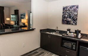 A modern kitchen with dark cabinetry, a granite countertop, a built-in microwave, and a coffee maker. - Holiday Inn Paducah Riverfront by IHG (Paducah)