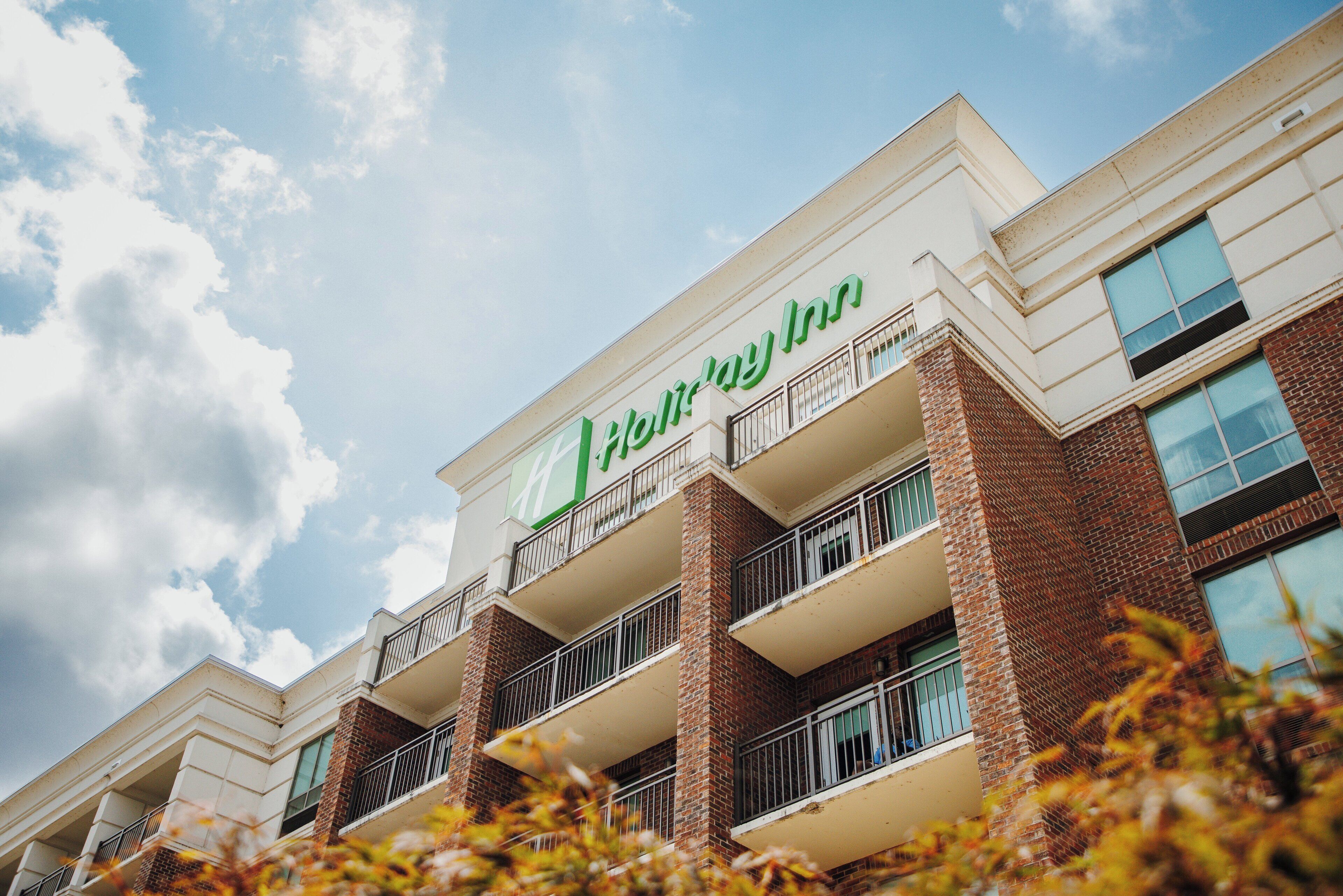 Un hôtel Holiday Inn avec une façade en briques, de nombreux balcons et un ciel dégagé.