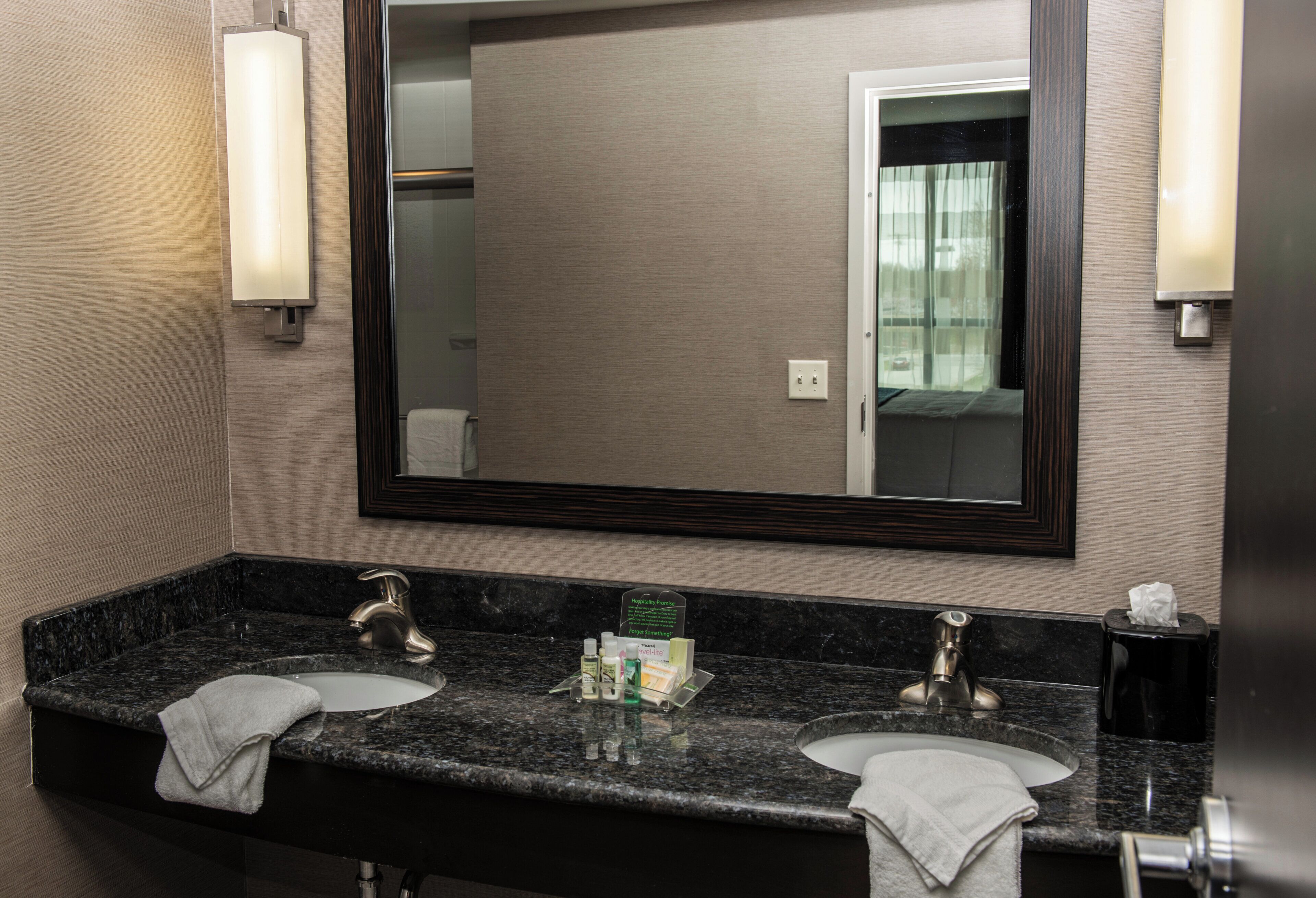 A bathroom with two sinks, a large mirror, and a towel rack.