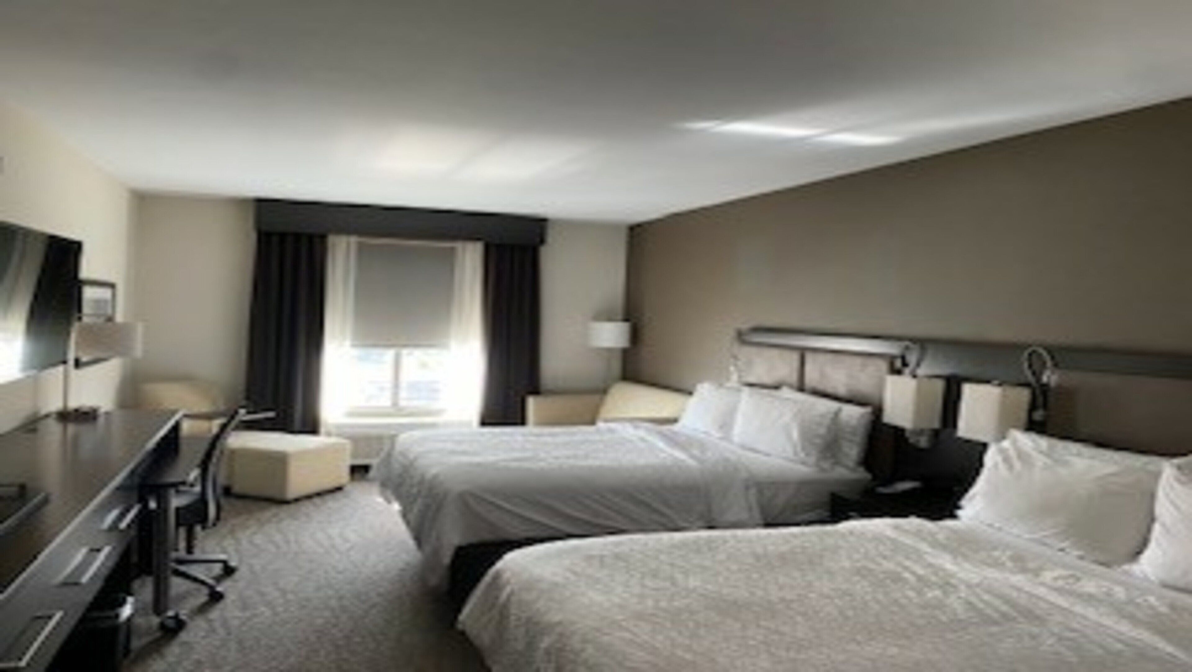Ein Hotelzimmer mit zwei Betten, einem Schreibtisch und einem Stuhl.
