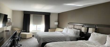Ein Hotelzimmer mit zwei Betten, einem Schreibtisch und einem Stuhl.