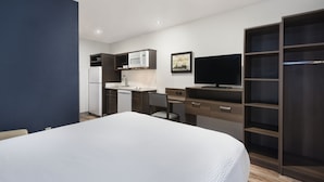 Une chambre d’hôtel moderne équipée d’un lit, d’une kitchenette, d’un bureau et d’une télévision.