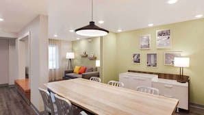 Une chambre d’hôtel moderne comprenant un coin repas, un canapé, un bureau et une kitchenette.