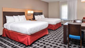 A hotel room with two beds, a desk, and a chair.