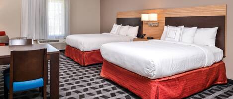 Ein Hotelzimmer mit zwei Betten, einem Schreibtisch und einem Stuhl.