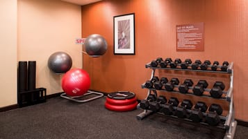 Ein Fitnessraum mit Trainingsgeräten, darunter ein roter Gymnastikball, zwei große Gymnastikbälle und ein Dumbbell-Ständer.