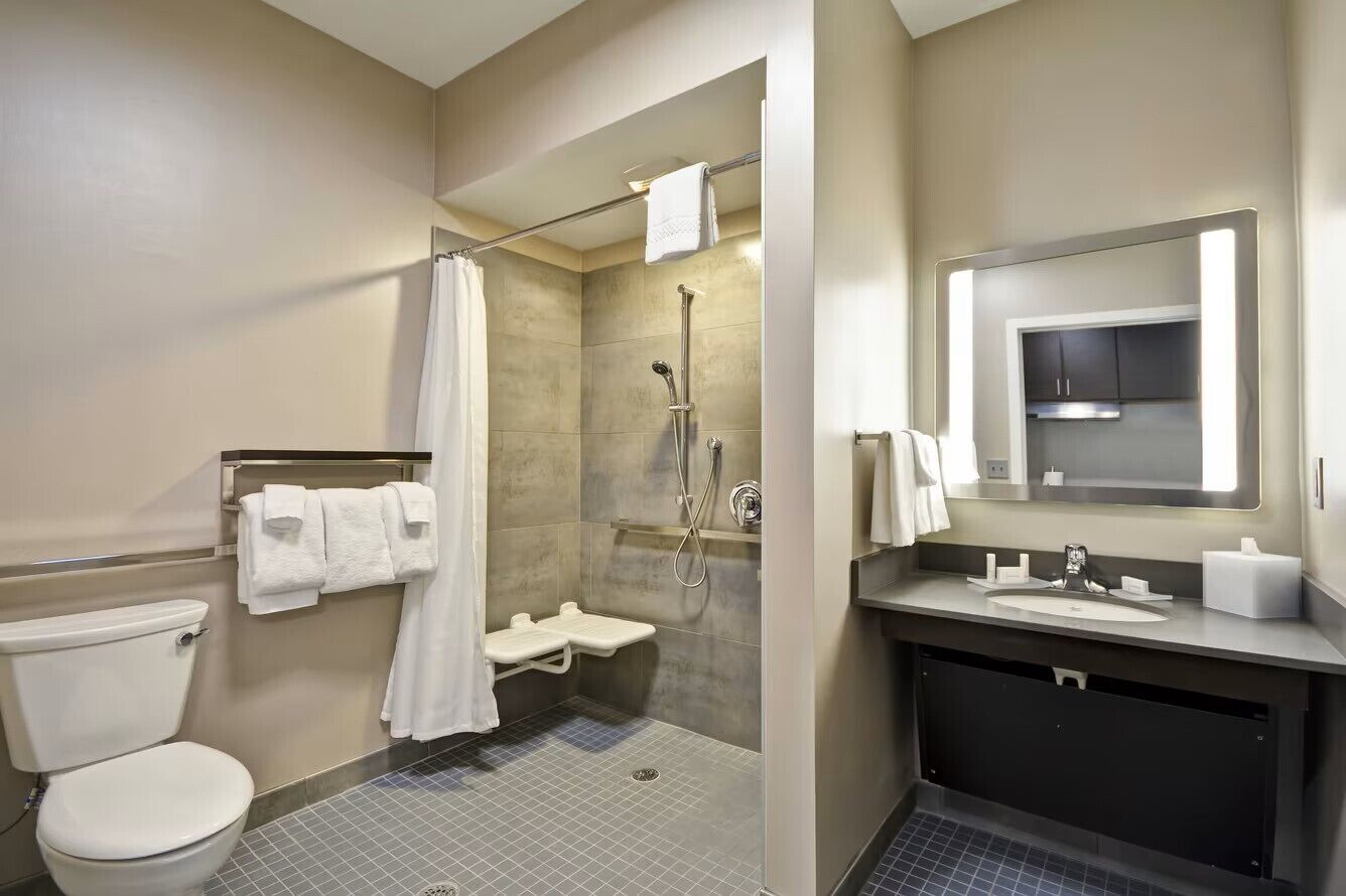 A bathroom with a toilet, shower, and sink.