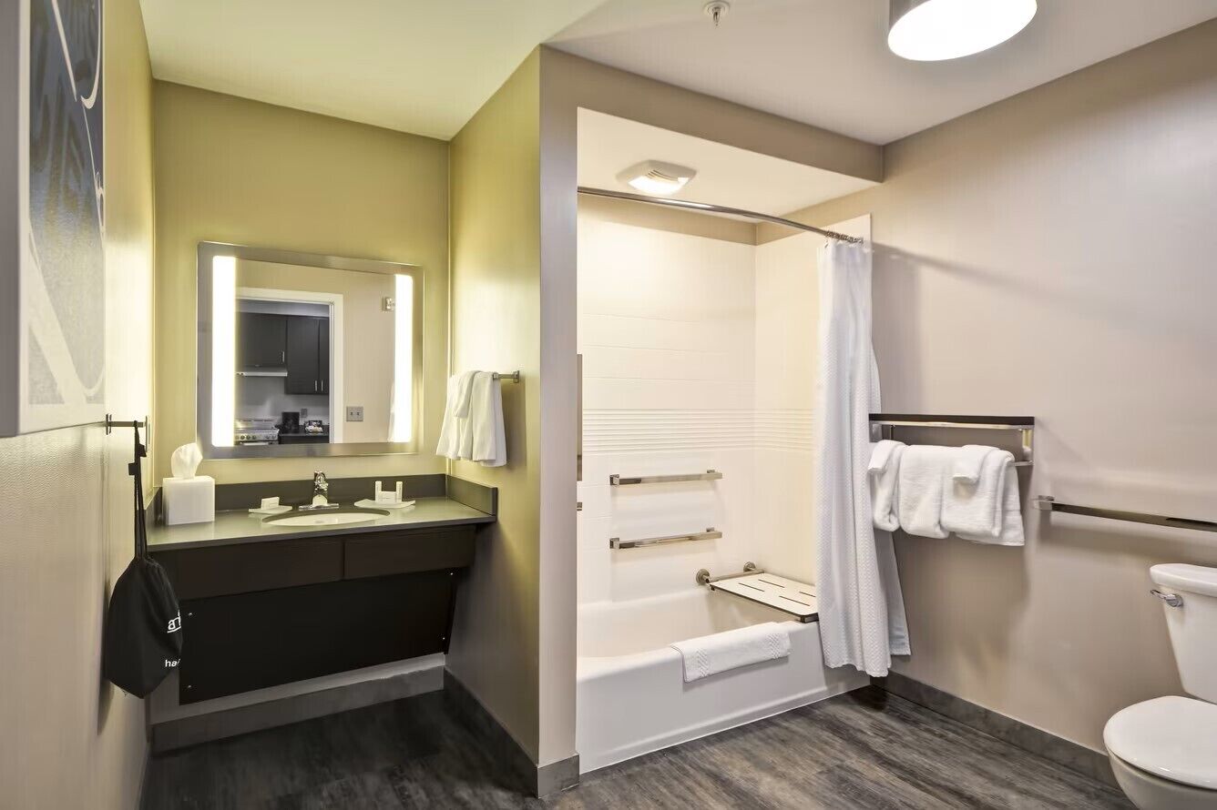 Un baño moderno con bañera, ducha, inodoro y tocador con espejo.