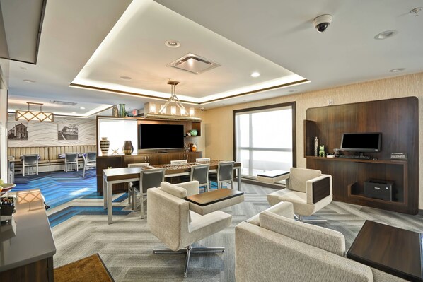 A modern hotel room with a dining area, a flat-screen TV, and comfortable seating.