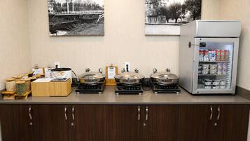 A kitchenette with a coffee machine, a food dispenser, and a refrigerator stocked with beverages.