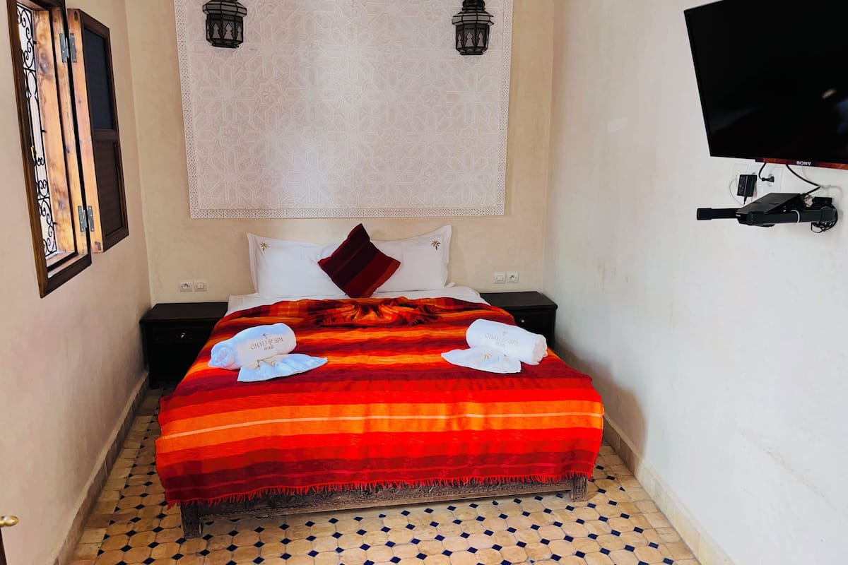 Een hotelkamer met een bed, een televisie en een wandlamp.
