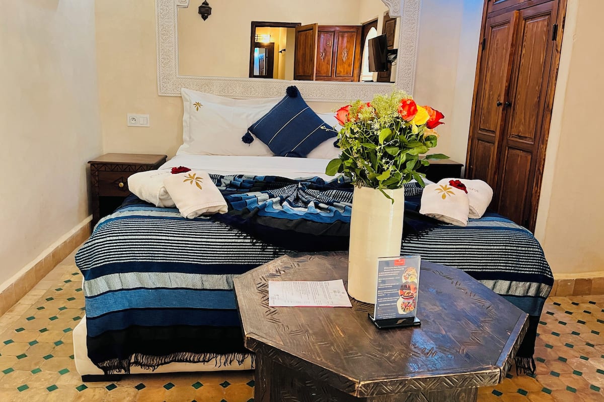 Een hotelkamer met twee bedden, een nachtkastje, een tafel met een menukaart en een vaas met bloemen.