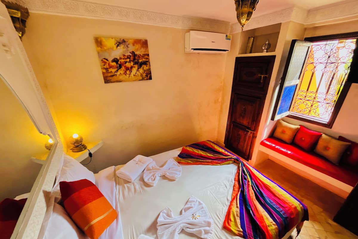 Hotelkamer met een bed, een bank, een schilderij, een airconditioner en een raam met uitzicht.