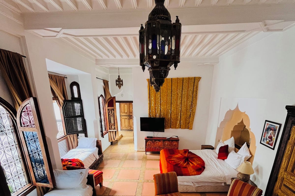 Een traditionele kamer met een bank, een bed, een televisie en een decoratieve hanglamp.
