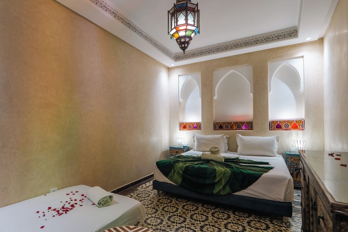 A hotel room with a bed, a bedside table, a decorative wall, and a patterned floor.