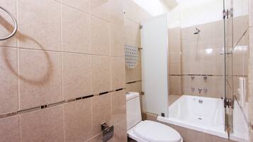 A bathroom with a toilet, a glass-enclosed shower, and a bathtub.