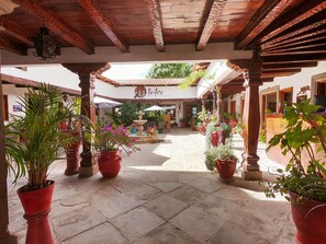 A courtyard with a tiled floor, potted plants, a fountain, and a building with a sign reading "Tintica Restaurante". - Real Carretero (Tapalpa)