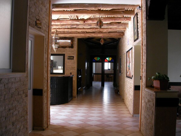 A hallway with a checkered floor, wooden ceiling, and a reception desk.