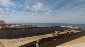 A rooftop with a view of the sea, featuring concrete structures and a satellite dish.