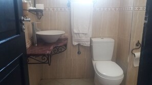 A small bathroom with a white sink, a toilet, and a towel hanging on the wall. - Hotel Safa (Sidi Ifni)