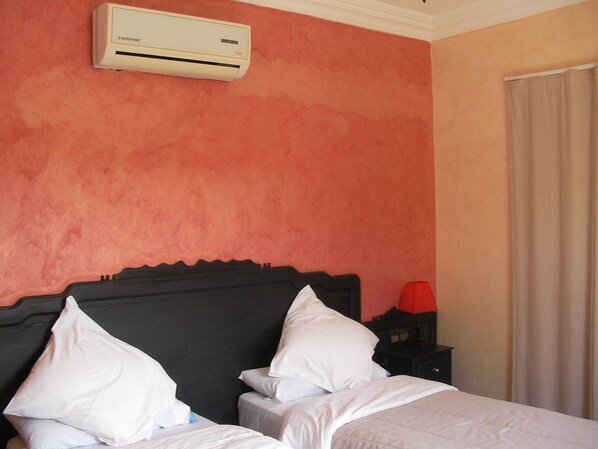 A hotel room with a bed, a nightstand, a lamp, and an air conditioning unit on the wall. - Hotel Safa (Sidi Ifni)