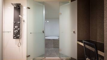 A modern bathroom with a glass shower enclosure, a visible toilet, and a chair.