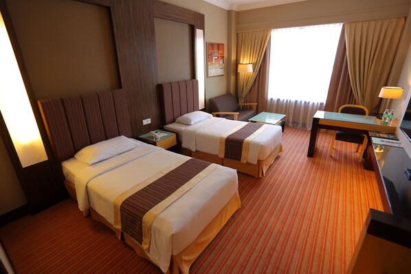 A hotel room with two beds, a desk, a chair, and a TV. - Dynasty Hotel Miri (Miri)