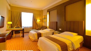 An exclusive deluxe twin room with two beds, a desk, a chair, and a TV. - Dynasty Hotel Miri (Miri)