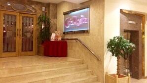 A hotel entrance with a neon sign reading "Cafe Rosita," a staircase, and a reception desk with a red tablecloth. - Dynasty Hotel Miri (Miri)