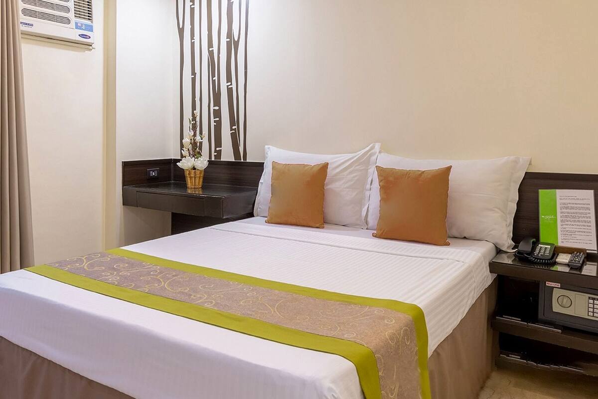 A hotel room with a bed, bedside table, and a telephone.