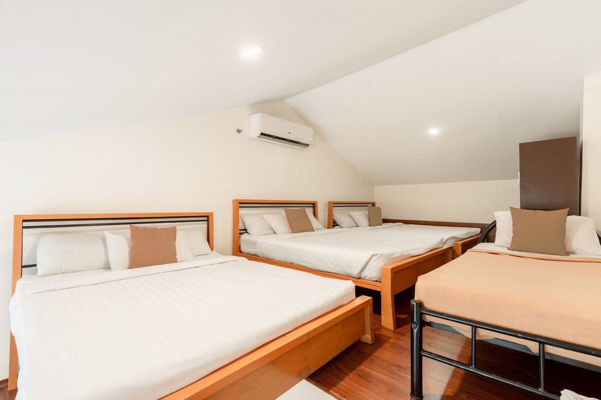 A room with three wooden beds, each with white bedding and brown pillows.