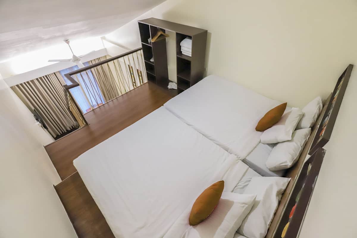 A bedroom with two beds, a wardrobe, and a ceiling fan.