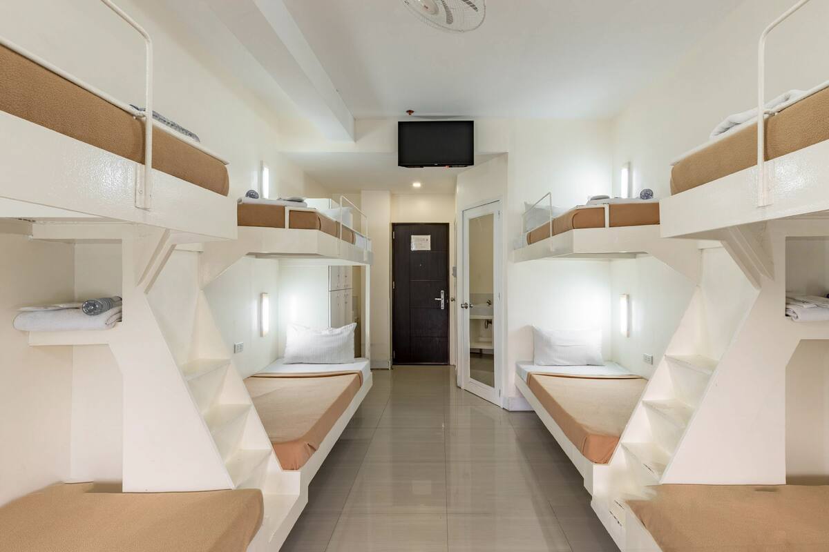 A corridor with bunk beds, a television, and a door leading to a bathroom.