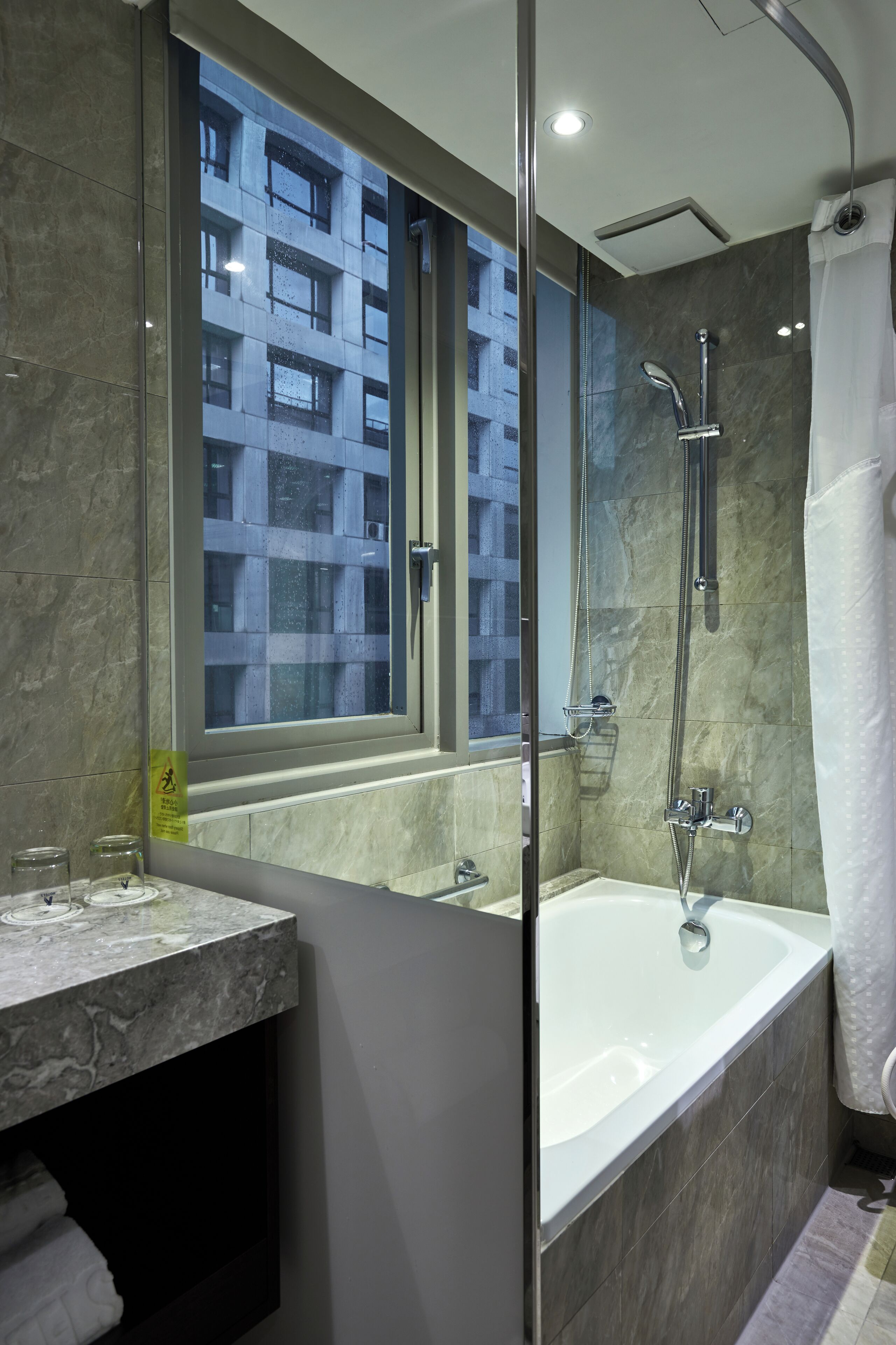A modern bathroom with a glass-enclosed shower, a large bathtub, and a vanity with a mirror.