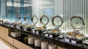 A buffet with various food stations, including hot and cold options, arranged in a modern setting with glass partitions. - K Hotels Taipei Tianjin (Taipei)