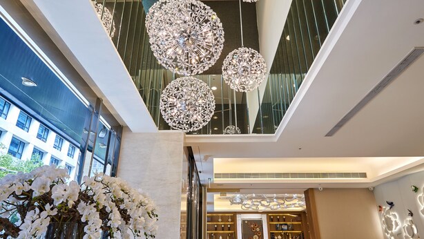 A modern hotel lobby with a high ceiling, large chandeliers, a reception desk, and a view of the building's exterior. - K Hotels Taipei Tianjin (Taipei)