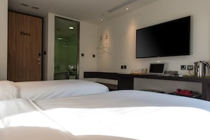 A hotel room with two beds, a television, a desk with a computer, and a coffee maker.