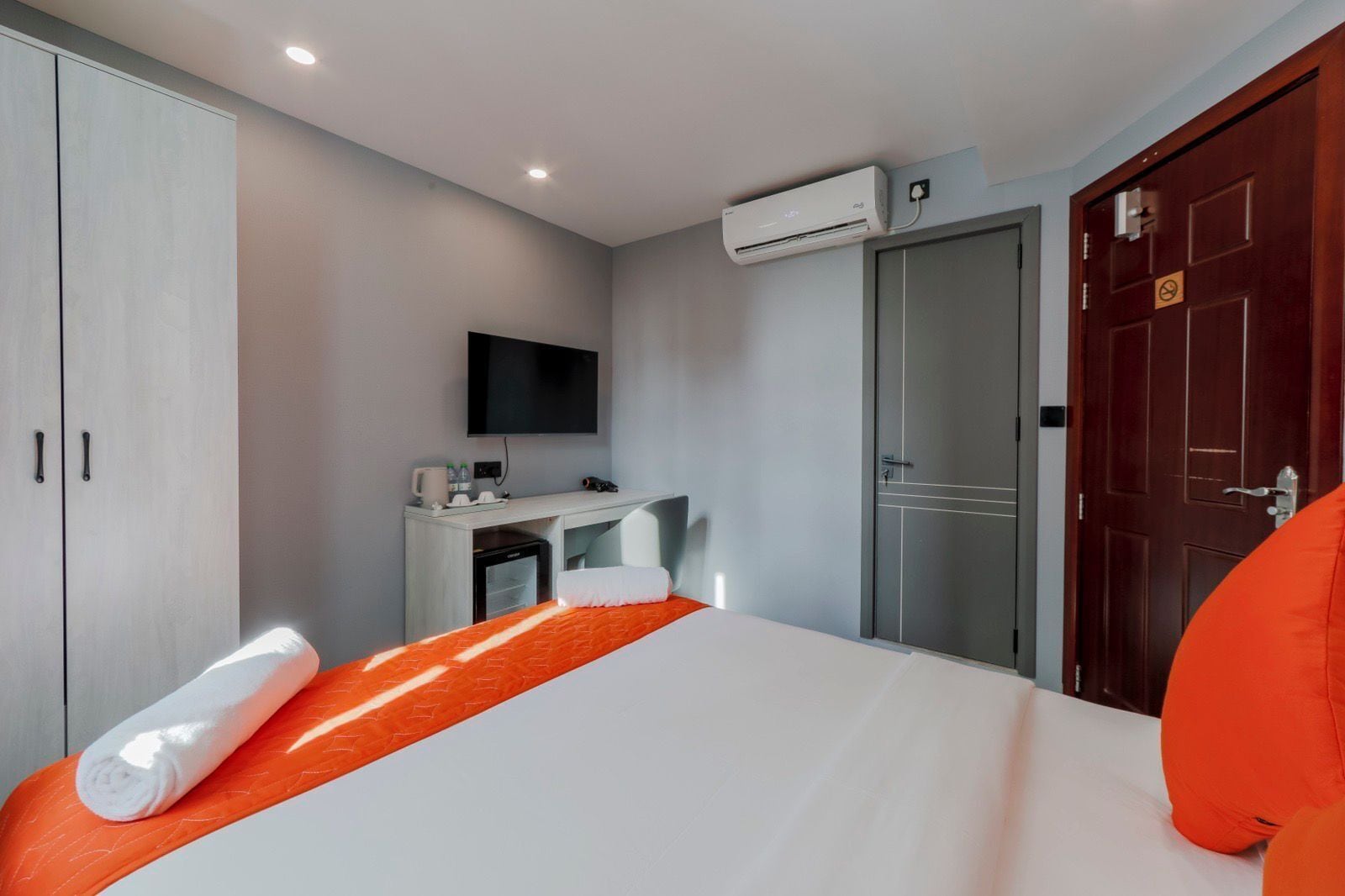 Habitación de hotel con cama, escritorio con televisor de pantalla plana, aire acondicionado y armario.