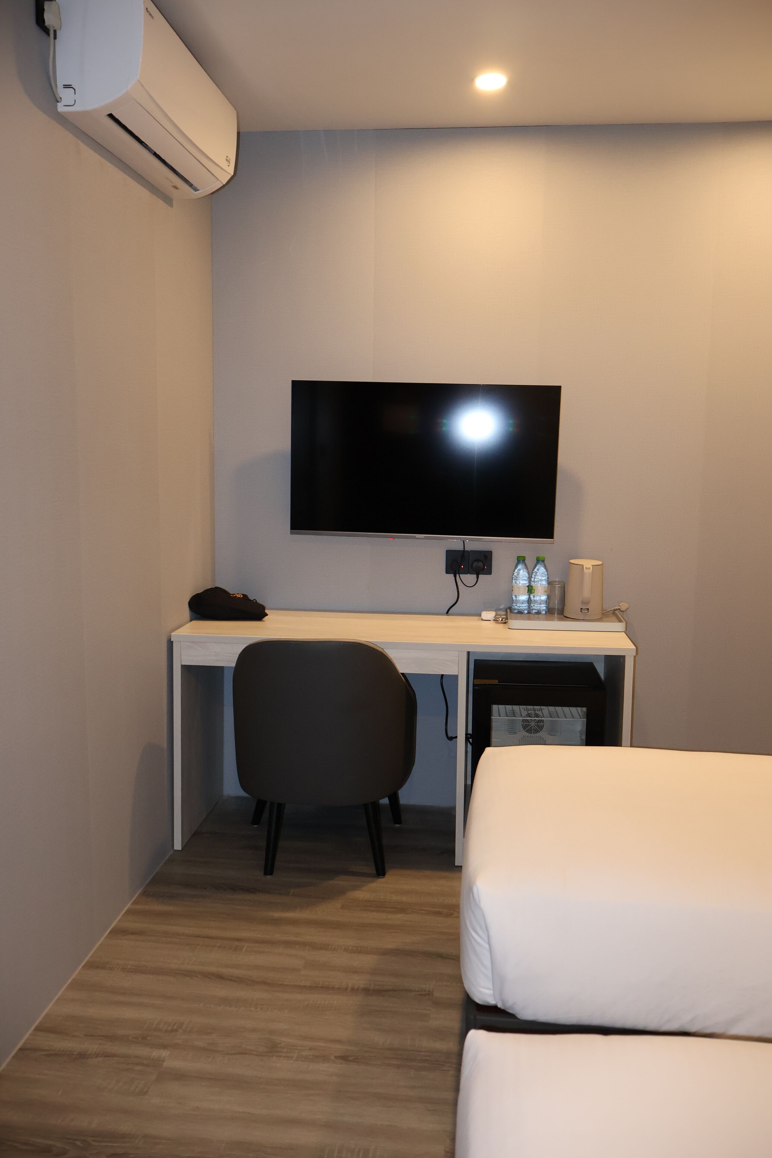 Una habitación de hotel con escritorio, televisor de pantalla plana, una silla y dos camas.