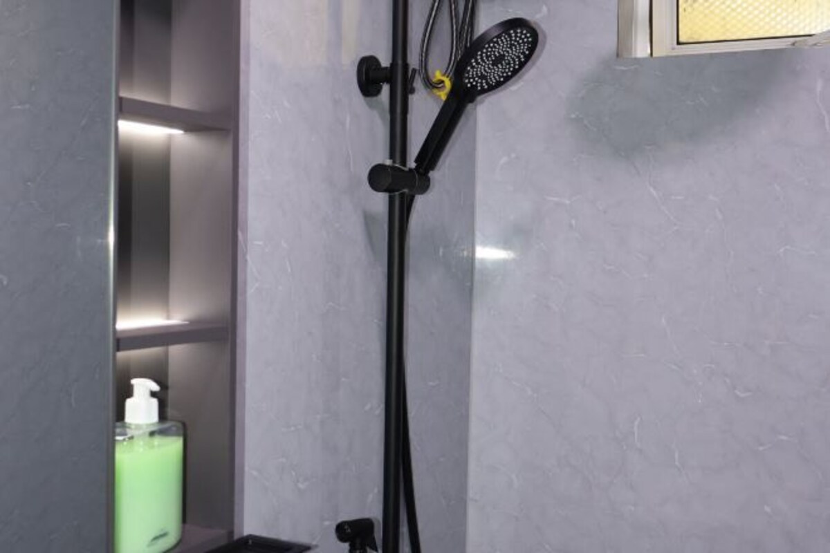 Een badkamer met een douche, een fles groene vloeibare zeep en een haarborstel.