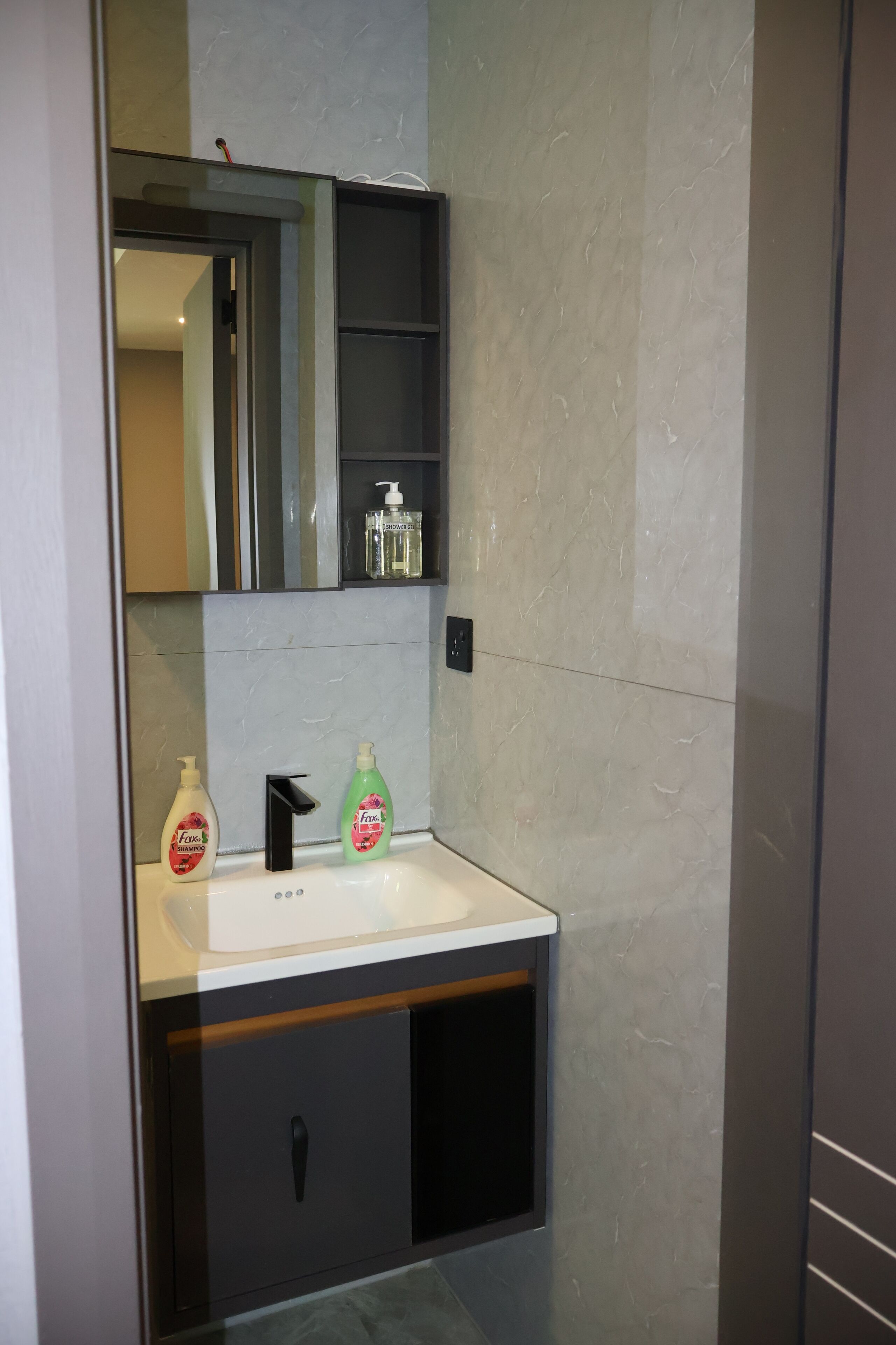 Een badkamer met een wit wastafel, een zwarte kraan en twee flessen shampoo.