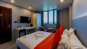 Une chambre d’hôtel avec un lit, un bureau, une télévision et une fenêtre donnant sur un paysage agréable.