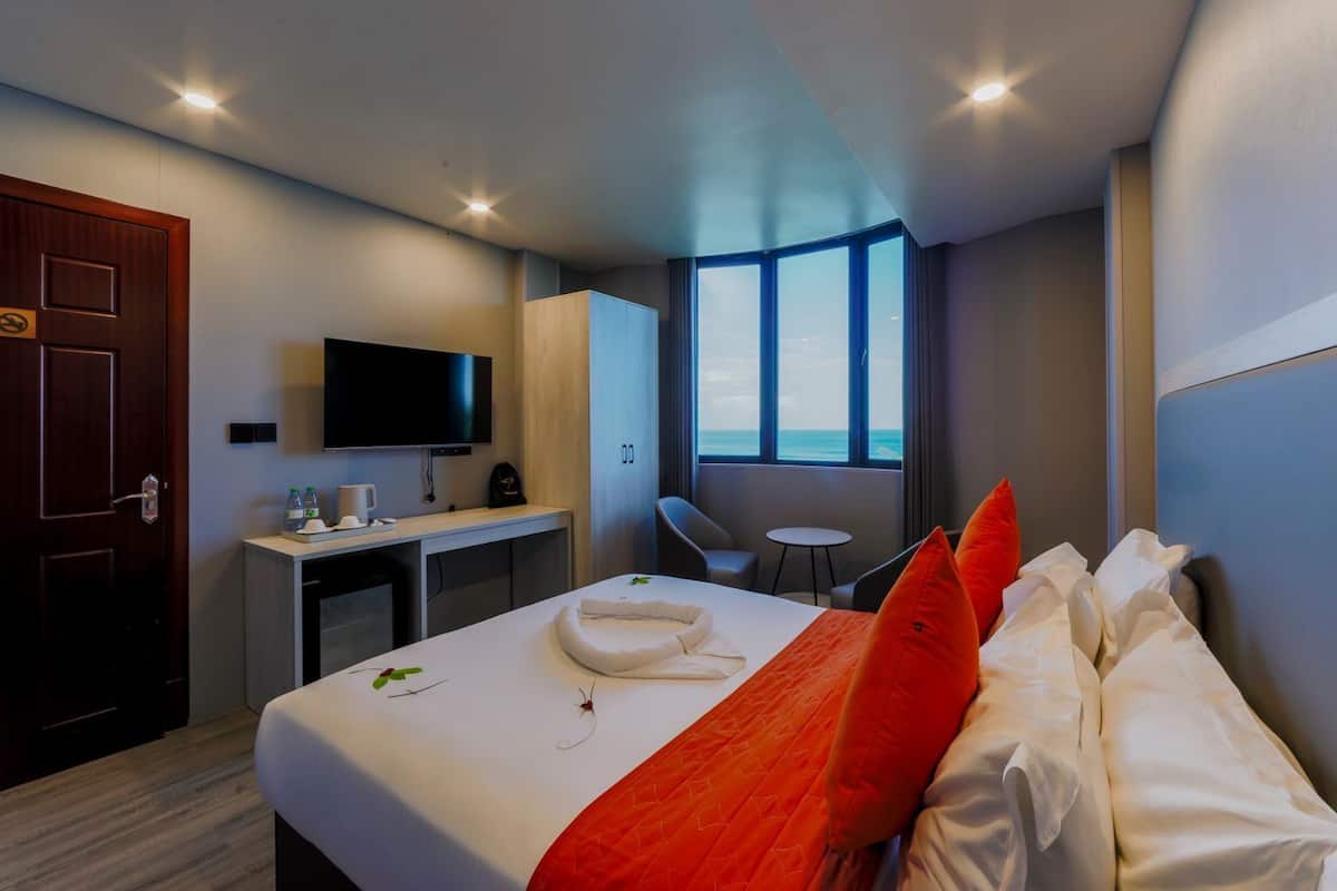 A hotel room with a bed, a desk, a TV, and a window with a view.